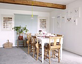 Dining table with pew chairs under ceiling beam of contemporary Staffordshire cottage, England, UK