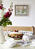 Erdbeer-Biskuitkuchen und Schnittblumen mit Teetasse und Zuckerdose auf dem Tisch, Oxfordshire, England, UK