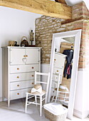 Full length mirror with chest of drawers in corner of bedroom in barn conversion, Oxfordshire, England, UK