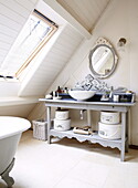 Waschbecken und ovaler Spiegel im Dachgeschoss-Badezimmer einer umgebauten Scheune, Oxfordshire, England, UK