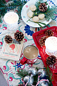 Tasse Tee und Mince Pies mit Tannenzapfen und Tannennadeln auf blumenbesticktem Stoff in einem Landhaus in Devonshire, Großbritannien