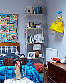 Penguin statue on chair at foot of bed with book shelving in London family home England UK