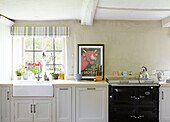 Silver kettle on hob of black range oven with Belfast sink in kitchen of Oxfordshire farmhouse England UK