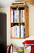 Wall mounted crate for cookery books in kitchen of Surrey farmhouse England UK