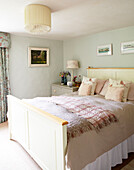 Double bed with pink cushions in pastel green bedroom of Surrey farmhouse England UK