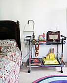 Vintage lamp and radio on chrome service trolley used as bedside table in boy's room of London townhouse England UK