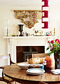 Wooden dining table in front of fireplace with architectural salvage in London townhouse England UK