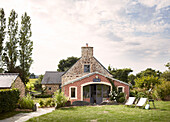 Deck chairs and barbecue set in garden of rural Brittany school conversion with brick extension France