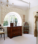 Vintage hat box on antique chest of drawers at arched bedroom window of traditional country house Welsh borders UK