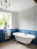 Freestanding bath in blue panelled bathroom of rural Oxfordshire cottage England UK