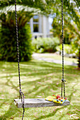Märchenbuch und Spielzeug auf einer Baumschaukel im Garten von Warkworth in Auckland auf der Nordinsel Neuseelands