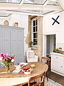 Exposed stone wall with window detail in Bicester kitchen with wooden oval-shaped table Oxfordshire England