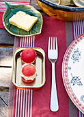 Gefüllte Tomaten und blattförmige Butterdose auf einem Tisch in der Bretagne Frankreich