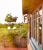 Garden planter and windows of Brittany farmhouse with distant deckchairs France