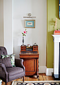 Polstersessel mit Vintage-Schreibkommode im Wohnzimmer eines Hauses in Kent, England UK
