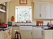 books on stool at butler sink below window with jars in Hexham farmhouse kitchen Northumberland UK