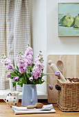 Pink flowers in jug with utensil basket in Northumbrian kitchen England UK