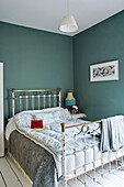 Vintage metal bed frame and quilt in green room of Birmingham home England UK