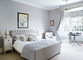 Framed artwork above pastel grey double bed with buttoned headboard in County Durham home England UK