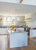 Weiße Pendelleuchten hängen über einer Kücheninsel in einem modernisierten Landhaus in Northumbria UK