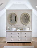 Ovale Spiegel über einem Doppelwaschbecken in einem modernisierten Landhaus in Northumbria UK