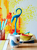 Blue flamingo with bowl and cup on dining table in studio, UK