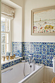 Blues tiled bathroom with framed artwork in Capheaton Hall, Northumberland, UK