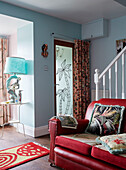 Red leather sofa with door curtain and wall deco in entrance room of County Durham home, North East England, UK