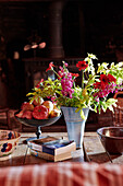 Cut flowers and apples with paperback books on table in Powys cottage, Wales, UK