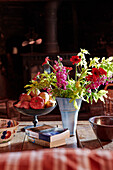 Schnittblumen und Äpfel mit Taschenbüchern auf einem Tisch in einem Landhaus in Powys, Wales, UK