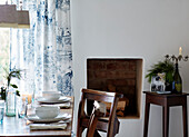 Pew chairs at place settings in dining room of Warwickshire farmhouse, England, UK