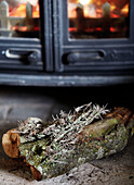 Fire log in front of wood burning stove in Warwickshire farmhouse, England, UK