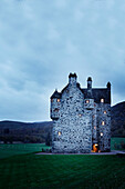 Lit windows in remote Scottish castle, UK