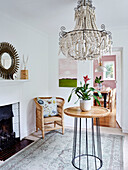 Bamboo chair at fireside with large beaded chandelier in Tunbridge Wells home, Kent, UK