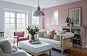 Buttoned sofa and armchair with cut lilies in pink living room Tunbridge Wells home, Kent, UK