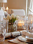 White tulips and vintage glassware on table set for Christmas dinner in, UK home