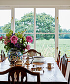Cut flowers on wooden table with view to Oxfordshire countryside, UK