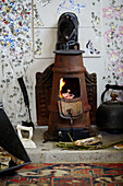 Kaminofen mit Feuer mit Anzündholz in einem Gartenhaus in Oxfordshire, UK