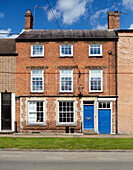 Three storey brick house with bright blue front door Deddington, Oxfordshire, UK