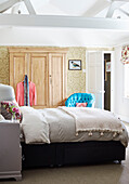 Doppelbett und hölzerner Kleiderschrank unter der Balkendecke in einem Haus in Deddington, Oxfordshire, UK