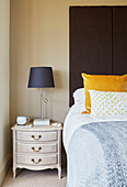 Braunes Kopfteil mit gelbem Kissen und grauer Lampe am Bett in einem Haus in Northumbria, UK