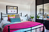 Bright pink blanket on bed in teen room with mirrored wardrobe 1960s dormer bungalow Holmfirth, West Yorkshire, UK