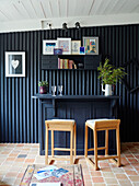 Stools at bar with wall mounted shelf on corrugated metal in Brittany cottage, France