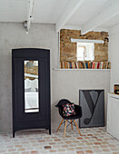 Black chair and wardrobe with shelf of books and framed letter 'y' in Brittany cottage, France