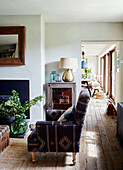 Upholstsred armchair with lamp on cabinet in Devon home, UK