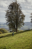 Frau beim Spazierengehen in der Nähe des Offas Dyke-Pfades an der ländlichen Grenze zwischen Radnorshire und Herfordshire, UK