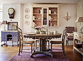 Wall mounted shelf and clock with wooden table and chairs in Cotswolds cottage, UK