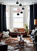 Cowhide rug and vintage leather sofas with frosted glass windows in Ramsgate living room Kent, UK