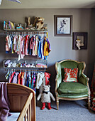 Clothes storage and green velvet armchair with cot in Devon nursery, UK