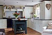 Teal island unit and brick floor in Devon kitchen, UK